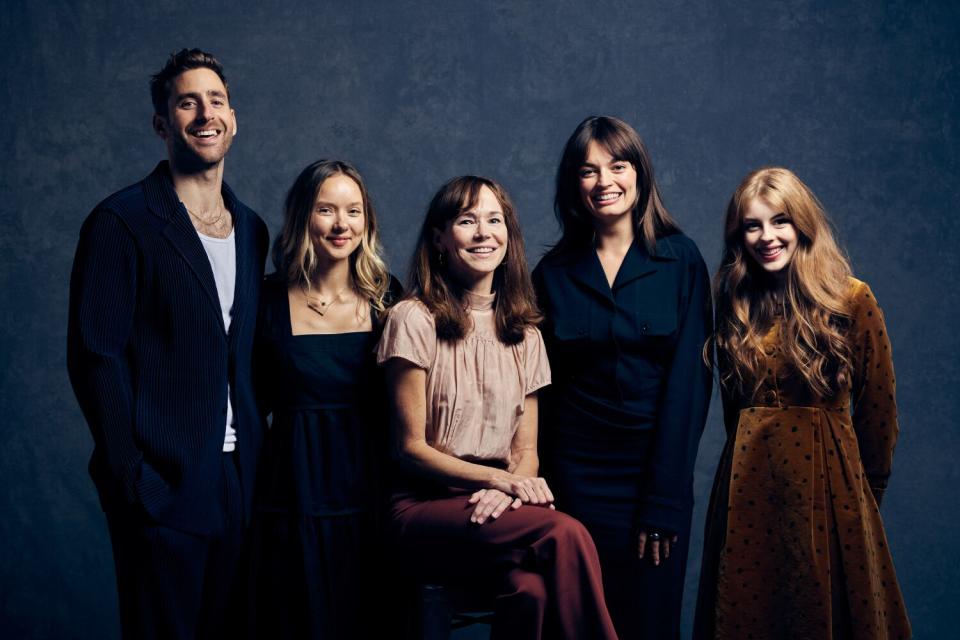 A group of four women and a man smile.