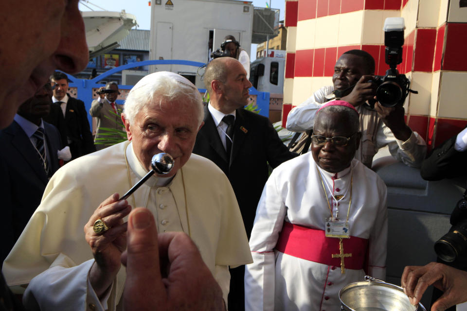 FILE - Pope Benedict XVI is accompanied by Archbishop of Cotonou Antoine Ganye, right, as he performs a ritual upon arriving at Notre Dame cathedral in Cotonou, Benin, on Nov. 18, 2011. Pope Emeritus Benedict XVI, the German theologian who will be remembered as the first pope in 600 years to resign, has died, the Vatican announced Saturday. He was 95. (AP Photo/Rebecca Blackwell, File)