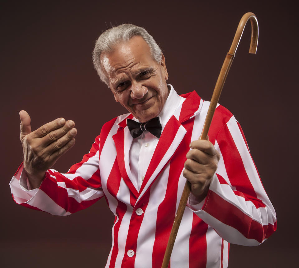 A carnival worker holding a cane and waving someone over