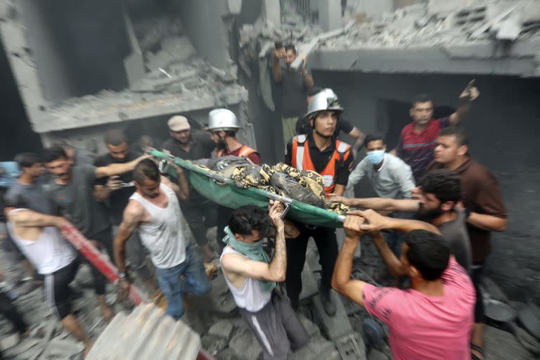 Residentes palestinos cargan un cuerpo sacado entre los escombros tras un bombardeo israelí en Gaza