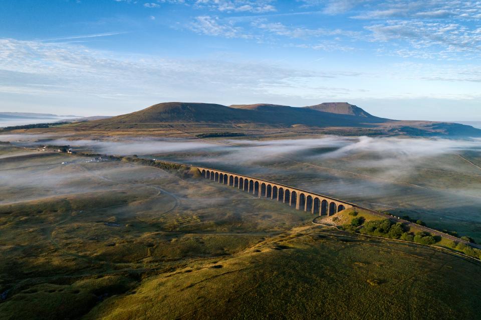 Misty morning at Ribblehead viaduct in Yorkshire dales with Ingleborough in the background.