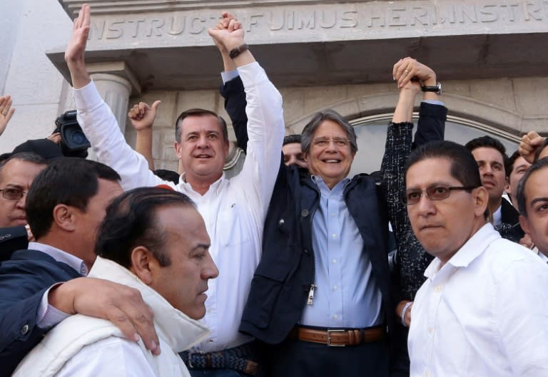 Ecuadorean presidential candidate for the CREO party, Guillermo Lasso (in blue blazer) raises his arms along with his running mate Andres Paez after the latter voted in Quito on February 19, 2017 during general election