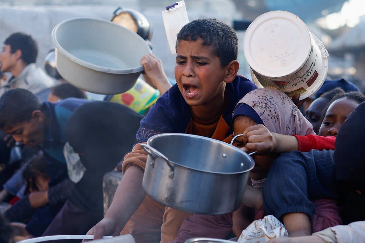 Palestinian children wait to receive food in Rafah (Reuters)