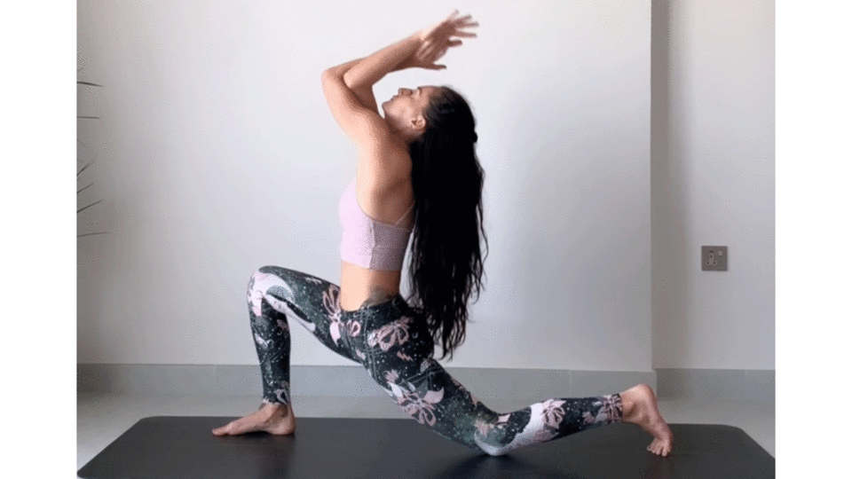 Woman kneeling on a yoga mat in low lunge stretching shoulders