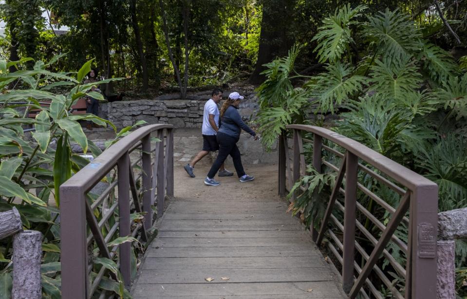 People walk past a footbridge on the Fern Dell Nature Trail