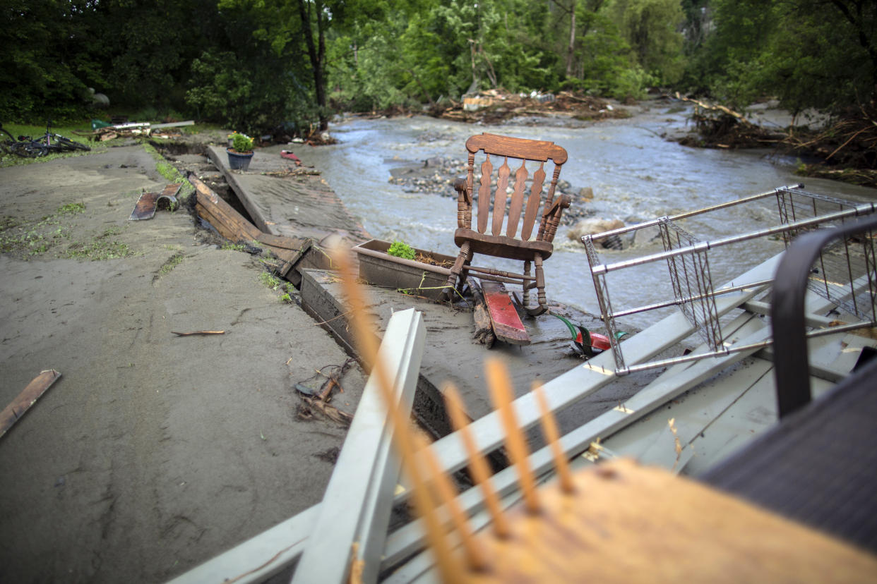 A rocking chair sits on the edge of a collapsed riverbank.