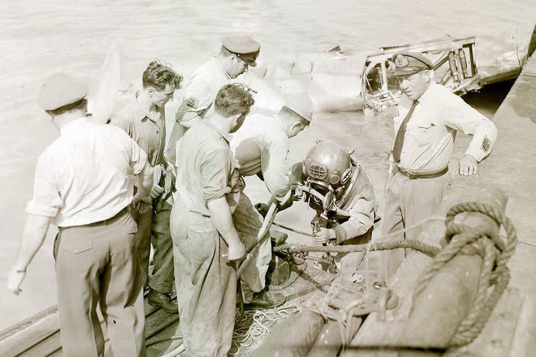 Un buzo se prepara para descender en las profundidades del río para tender los cables de amarre para recuperar el avión hundido el 31 de diciembre de 1957