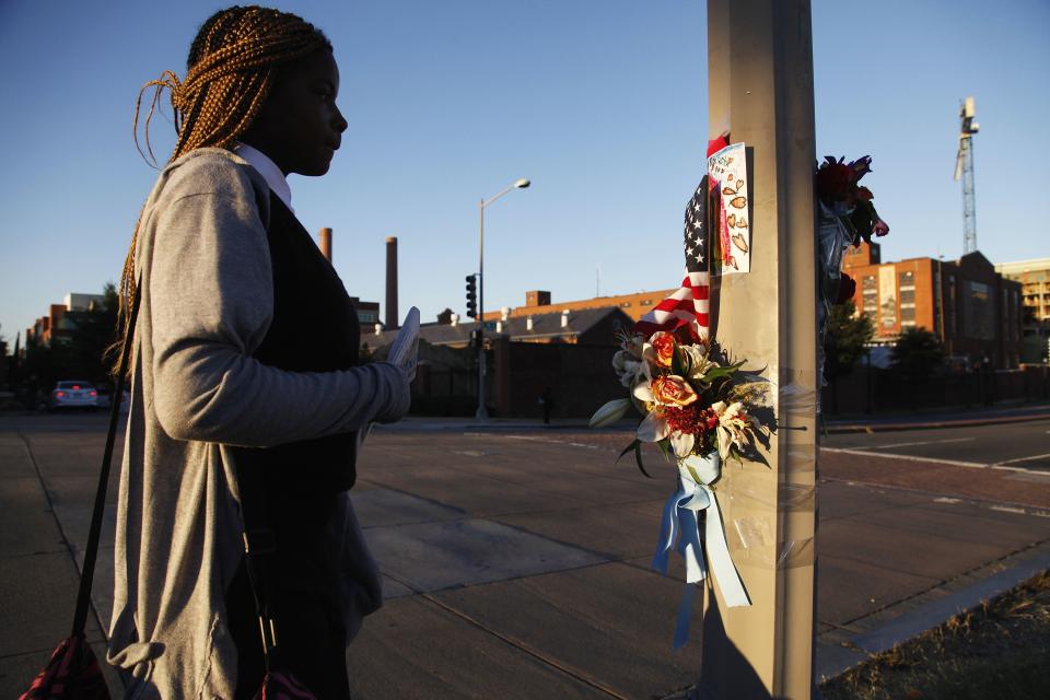 A woman stops to look at flowers, flags and a child's drawing left outside the Navy Yard installation after a gunman killed 12 people, in Washington