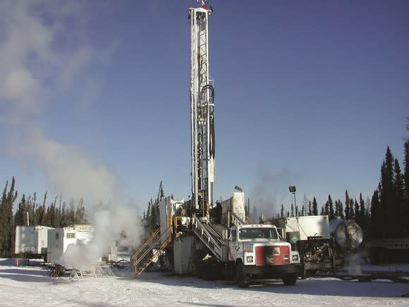 Oil rig in winter environment with support vehicles nearby.