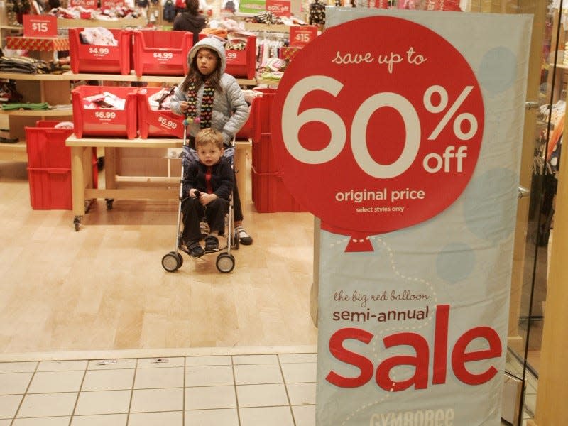 Two children stand near a 60 percent off sale sign at a Gymboree children's clothing store as shoppers buy gifts on Christmas Eve at the Beverly Center shopping mall in Los Angeles, California December 24, 2008.  REUTERS/Fred Prouser       (UNITED STATES) - RTR22TW9