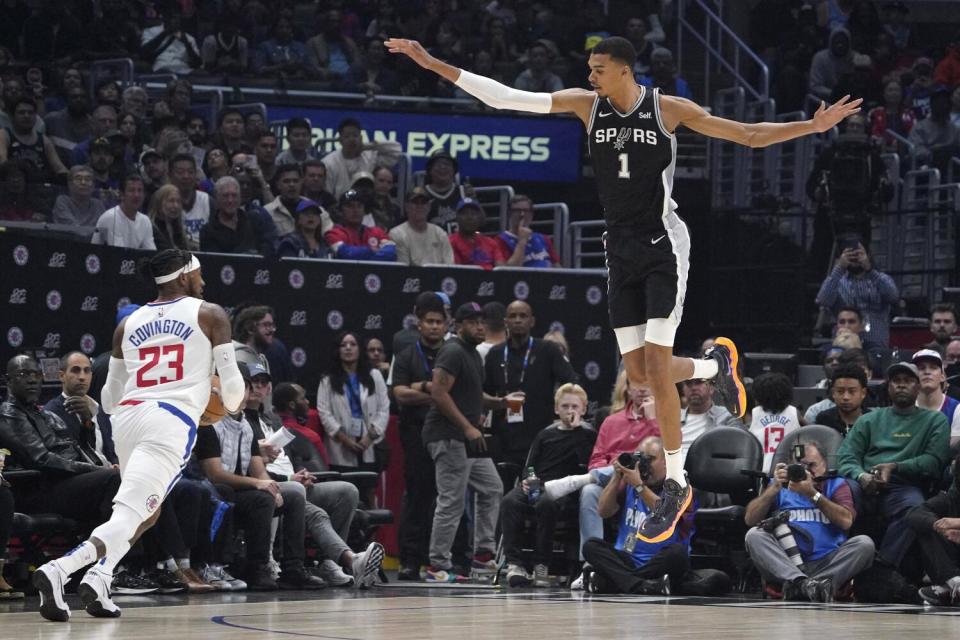 Victor Wembanyama leaps and holds out a long arm over Clippers forward Robert Covington