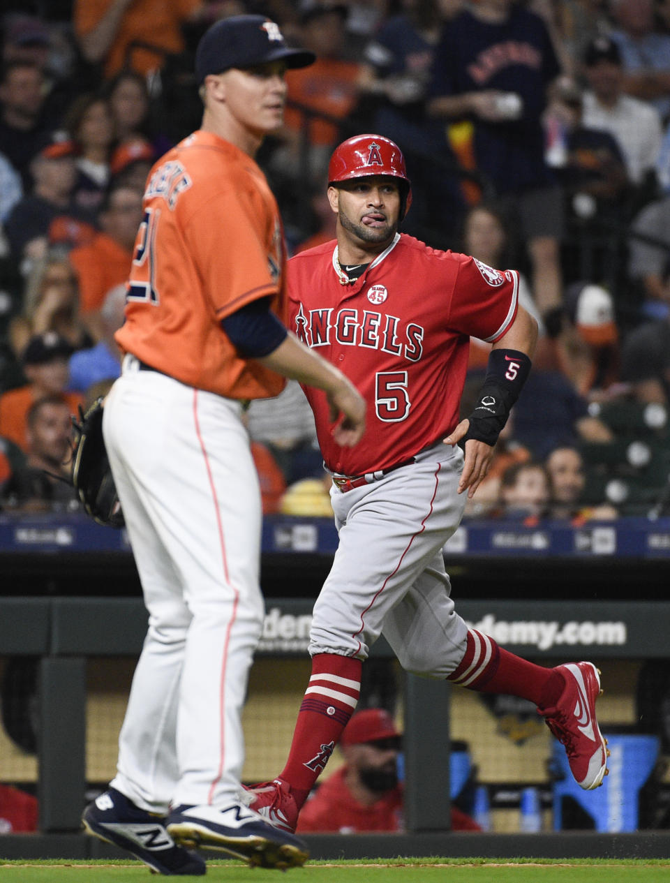 Los Angeles Angels' Albert Pujols (5) runs home to score on Andrelton Simmons' two-run double as Houston Astros starting pitcher Zack Greinke, left, watches during the fourth inning of a baseball game Friday, Sept. 20, 2019, in Houston. (AP Photo/Eric Christian Smith)