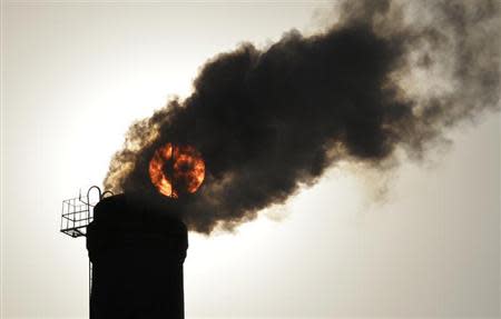 The sun is seen behind smoke billowing from a chimney of a heating plant in Taiyuan, Shanxi province December 9, 2013. REUTERS/Stringer