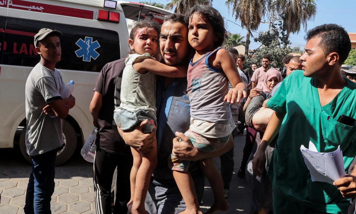 <span>A Palestinian man carries children wounded in an Israeli strike in the central Gaza strip ob Sunday.</span><span>Photograph: Ramadan Abed/Reuters</span>