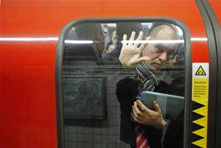 A passenger is squeezed up against a door in one of the few tube trains which became overcrowded during rush hour at Oxford Circus underground station in London February 5, 2014. REUTERS/Luke MacGregor