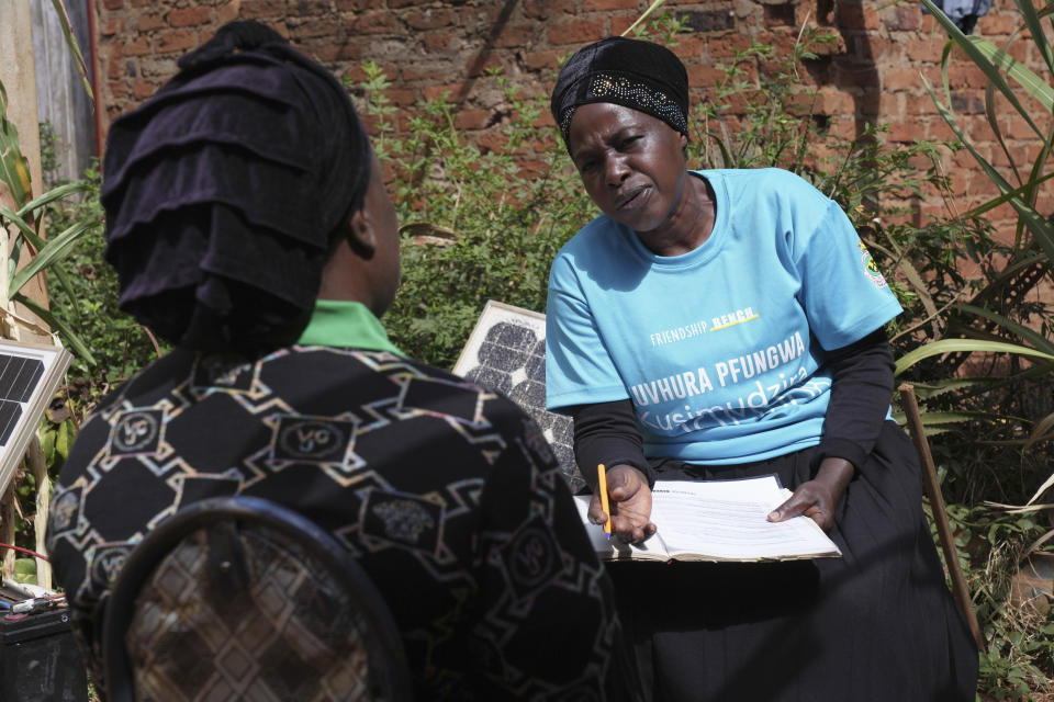 Siridzayi Dzukwa, a grandmother, right, talks to Tambudzai Tembo outside her house in Hatfcliffe on the outskirts of the capital Harare, Zimbabwe, Wednesday, May 15, 2024. In Zimbabwe, talk therapy involving park benches and a network of grandmothers has become a saving grace for people with mental health issues. Now the concept is being adopted in parts of the United States and elsewhere. (AP Photo/Tsvangirayi Mukwazhi)