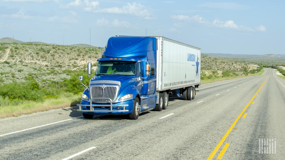 A blue tractor pulling a Landstar trailer