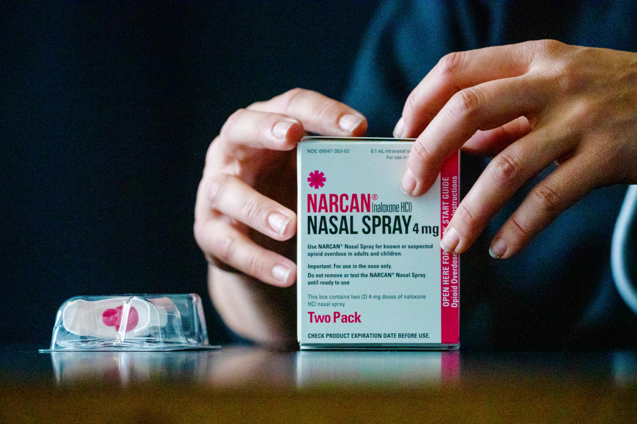 Narcan, seen here boxed and being touched by two hands, is now available over the counter