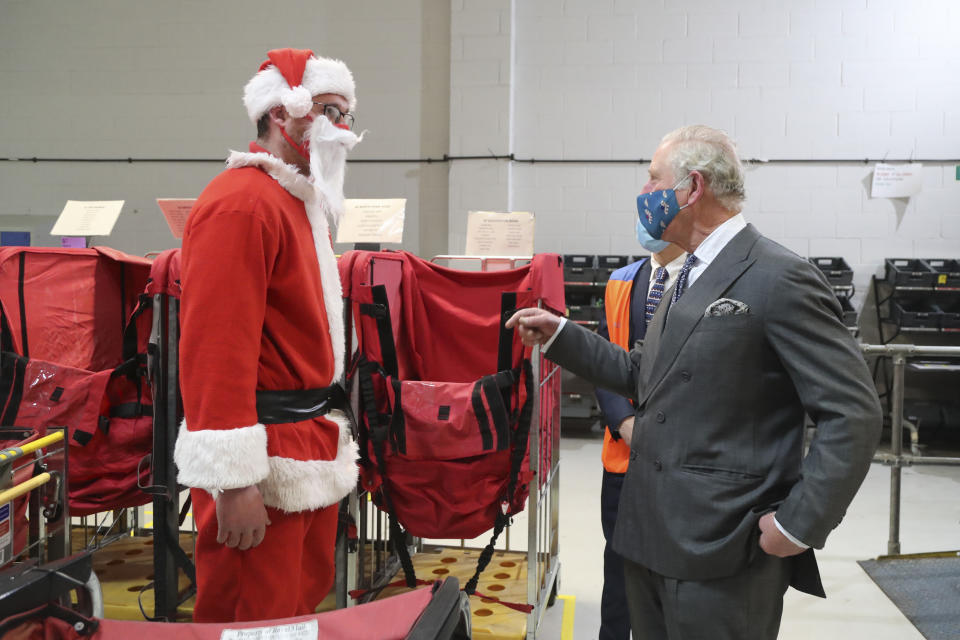 CIRENCESTER, ENGLAND - DECEMBER 18: Prince Charles, Prince of Wales, wearing a mask speaks to postal worker Tim Lafford (L) wearing a Father Christmas outfit during a visit to the Royal Mail's Delivery Office in Cirencester to recognise the vital public services that the country's postal workers provide, especially during the coronavirus pandemic and in the run-up to Christmas on December 18, 2020 in Cirencester, England.  (Photo by Geoff Caddick - WPA Pool / Getty Images)