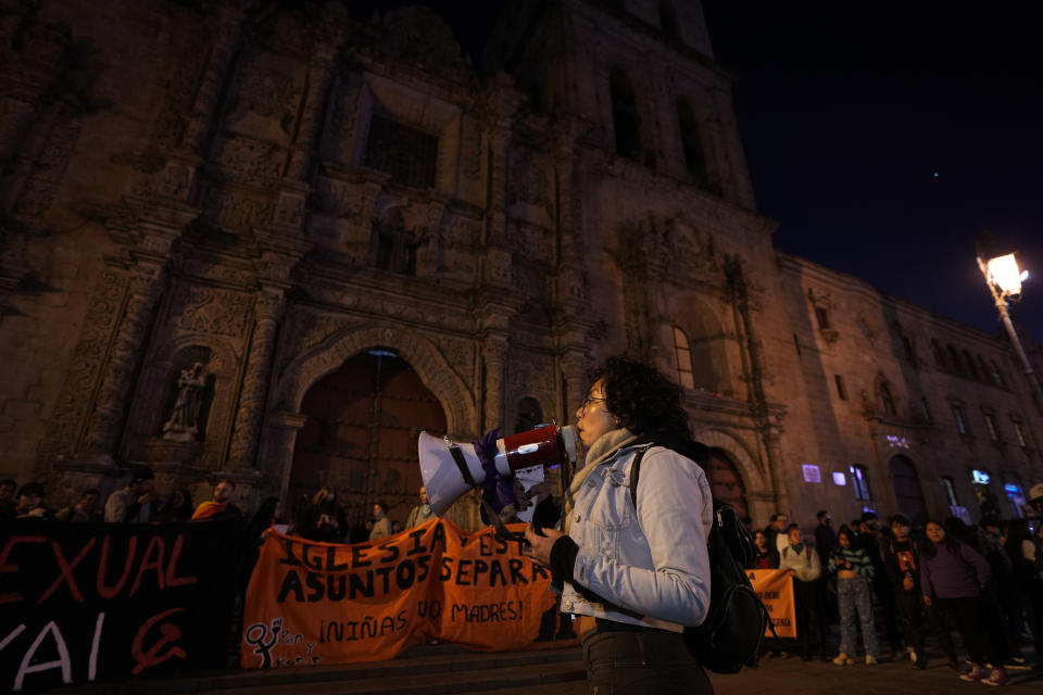 Una mujer usa un megáfono afuera de la Basílica de San Francisco durante una protesta para exigir justicia para las víctimas de sacerdotes pederastas en La Paz, Bolivia, el viernes 2 de junio de 2023. (AP Foto/Juan Karita).