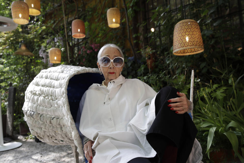 In this picture taken on Wednesday, April 17, 2019, Italian gallerist Rossella Orlandi sits on Spanish designer Nacho Carbonell's chair 'Re-evolution', made with recycled plastic from packaging for the "RO Plastic - Master's Pieces" exhibition, on the sidelines of Milan's Furniture Fair, in Milan, Italy. Scientists and environmental activists have been long raised the alarm on plastic pollution. Now, the high-end design world is getting in on the growing global effort to tackle plastic pollution -- by upcycling discarded objects into desirable one-off design pieces. (AP Photo/Luca Bruno)