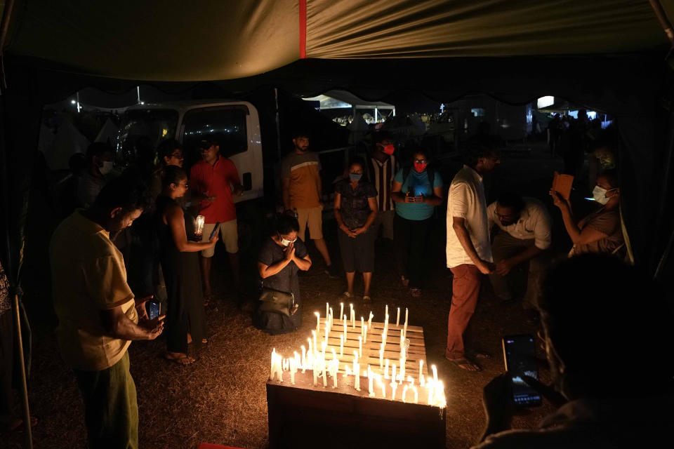 Sri Lankans hold candle light vigil condemning police shooting at protesters in Rambukkana, 90 kilometers (55 miles) northeast of Colombo, during a protest outside the president's office in Colombo, Sri Lanka, Tuesday, April 19, 2022. Sri Lankan police opened fire Tuesday at a group of people protesting new fuel price increases, killing one and injuring 10 others, in the first shooting by security forces during weeks of demonstrations over the country's worst economic crisis in decades. (AP Photo/Eranga Jayawardena)