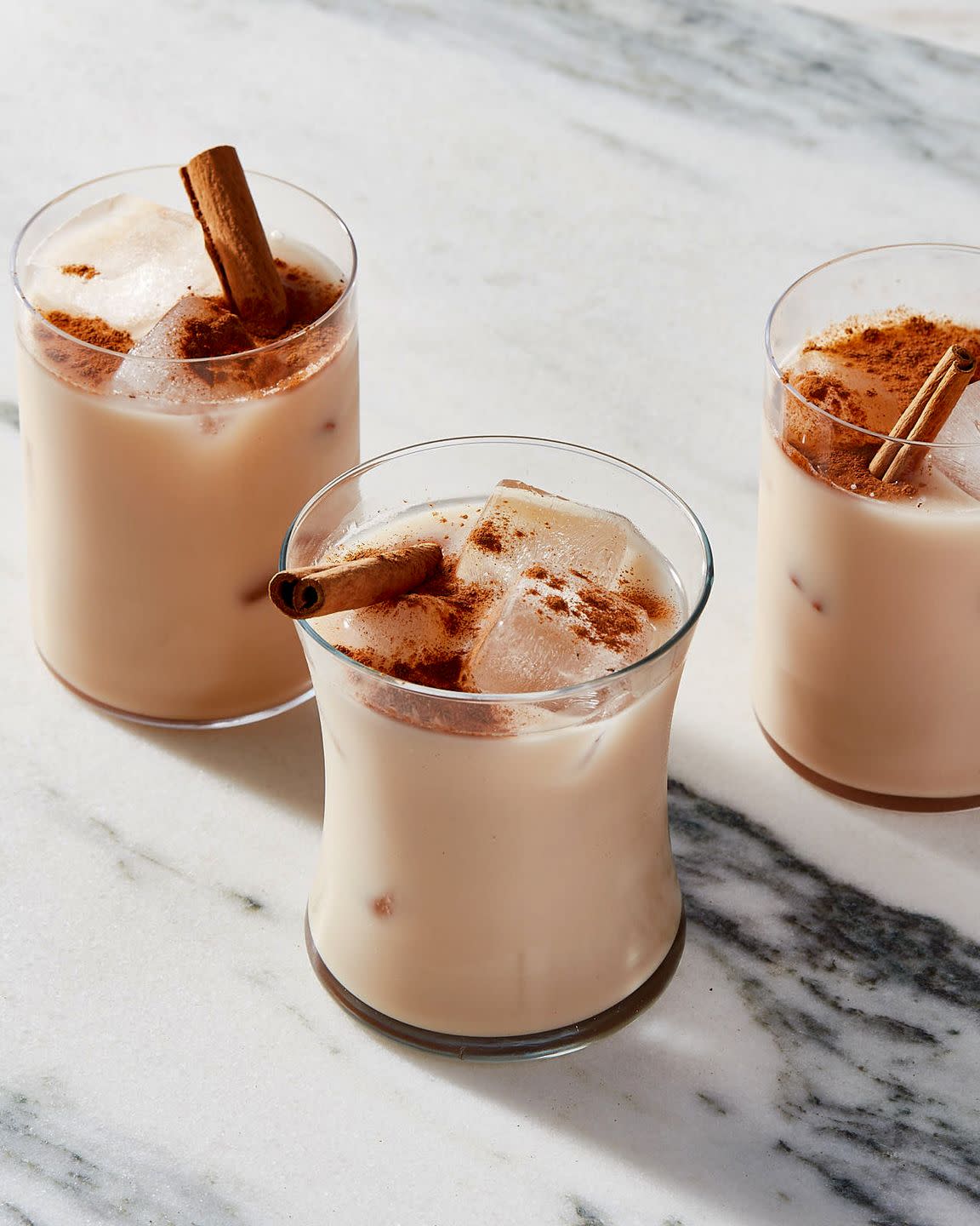 three glasses of horchata garnished with cinnamon sticks