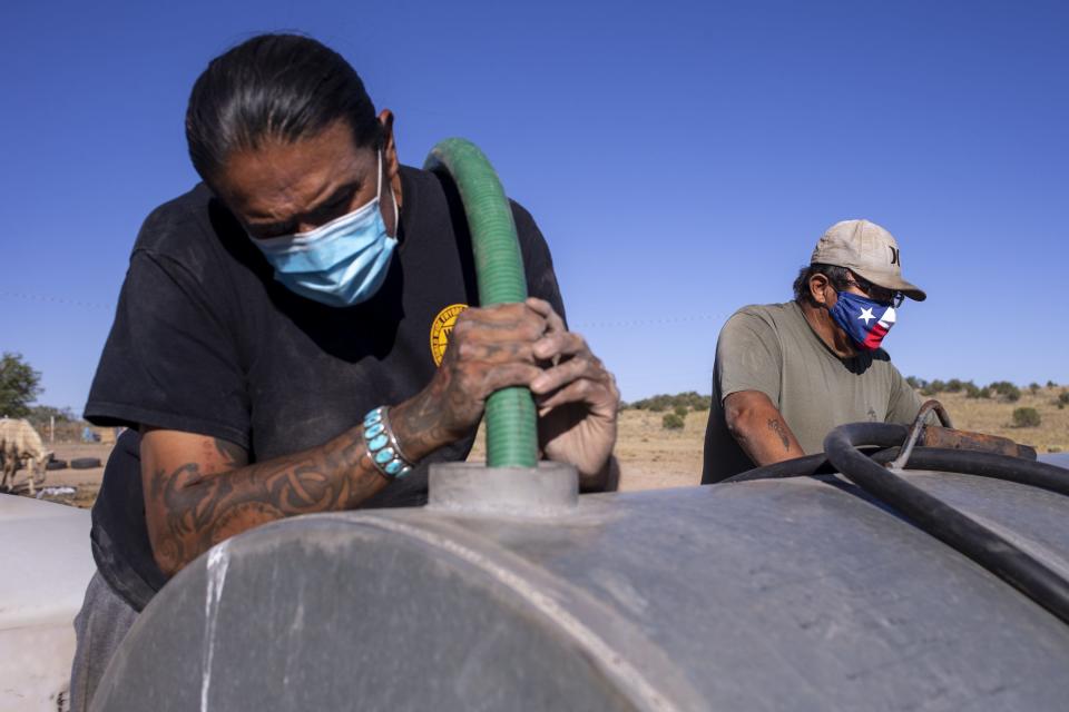 Jesse Slivers, 61, watches as Zoel Zohnnie fills his water tank on Sept. 1, 2020, in Steamboat, Ariz. Water Warriors United delivers water to families in need all across the Navajo Nation.