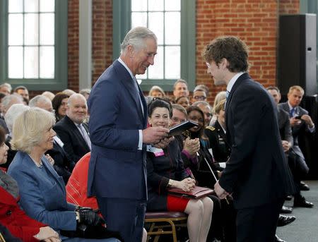 Louisville Orchestra conductor Teddy Abrams (R) presents the musical score to "Kentucky Royal Fanfare", after the orchestra performed it for Britain's Prince Charles (C) and Camilla, Duchess of Cornwall (L) at the Kentucky Center for African American Heritage in Louisville, Kentucky March 20, 2015. REUTERS/John Sommers II