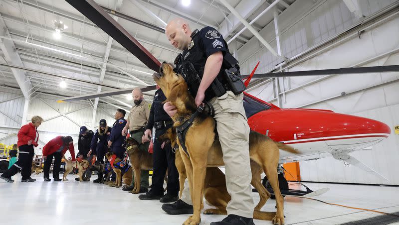 Woods Cross Sgt. Corey Boyle and his dog Ranger and other K9 handlers stand near a Intermountain Life Flight helicopter during a press conference in Salt Lake City on Tuesday, Feb. 20, 2024. Collaboration with local veterinarians, specialized animal hospitals and public safety agencies, Intermountain Life Flight is launching a specialized K9 air transport service for public agency service animals who are injured in the line of duty.