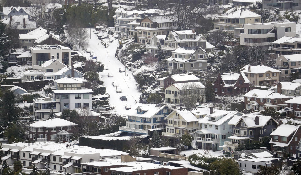 Streets, homes and cars remain snow-covered on one of Seattle's steeper hills, Queen Anne, Monday, Feb. 11, 2019. Schools and universities closed across Washington state and the Legislature cancelled all hearings as the Northwest dealt with snow and ice and prepared for more as a series of winter storms socked the region. (AP Photo/Elaine Thompson)