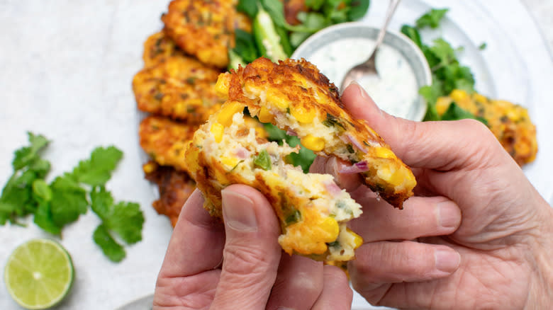 corn and jalapeño fritters with hands