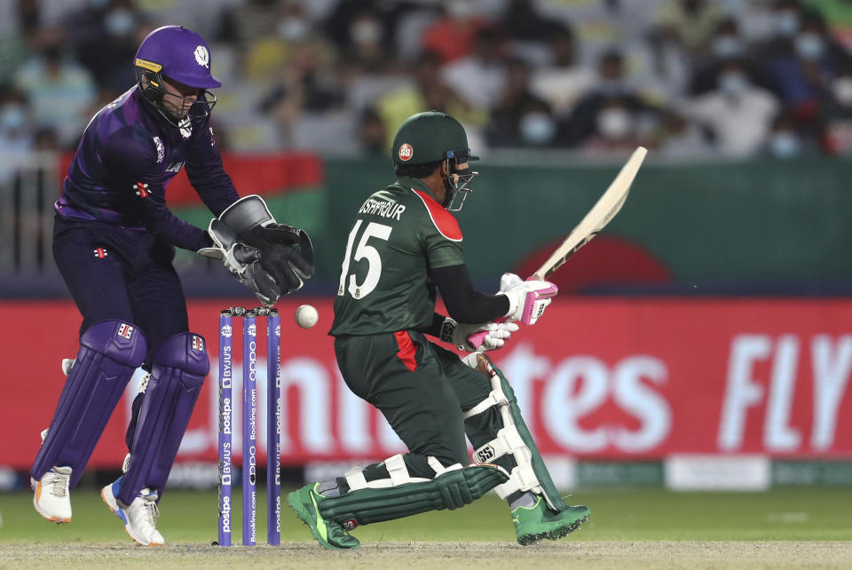 Bangladesh's batsman Mushfiqur Rahim, right, plays a reverse shot as Scotland's wicketkeeper Matthew Cross watches fields during the Cricket Twenty20 World Cup first round match between Bangladesh and Scotland in Muscat, Oman, Sunday, Oct. 17, 2021. (AP Photo/Kamran Jebreili)