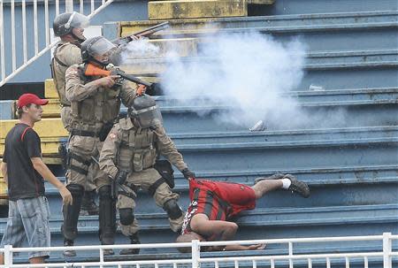 Policemen fire rubber bullets as they help an Atletico Paranaense fan during clashes between Vasco da Gama soccer fans and Atletico Paranaense fans at their Brazilian championship match in Joinville in Santa Catarina state December 8, 2013. REUTERS/Carlos Moraes