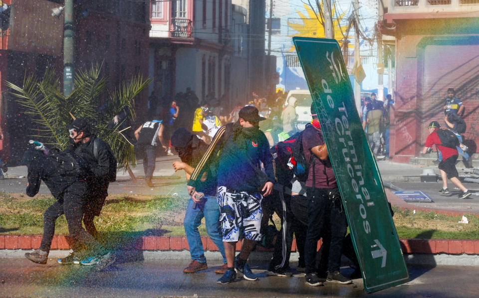 Demonstrators take cover with a traffic signal as they clash with security forces during a protest against Chile's government in Valparaiso, Chile on Oct. 28, 2019. (Photo: Rodrigo Garrido/Reuters)
