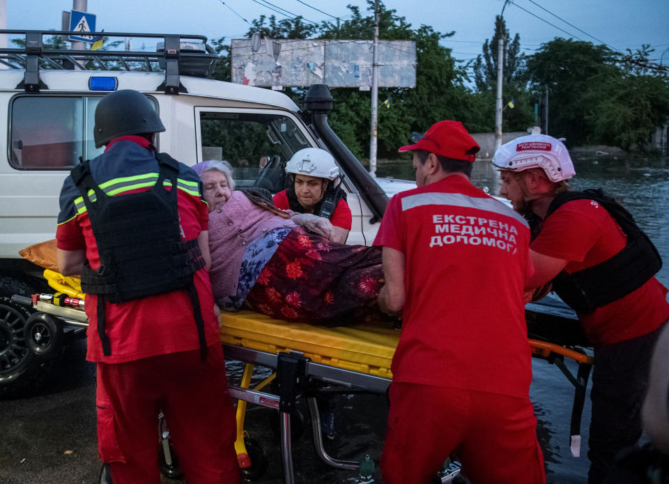 Red Cross volunteers help an elderly woman 