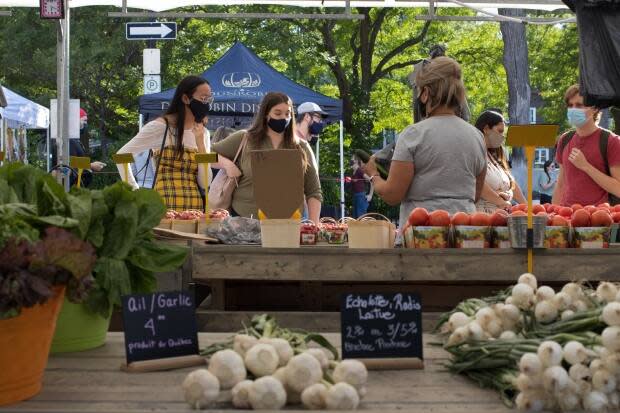 Customers buy produce from a vendor at the Parkdale Night Market in Ottawa. (Trevor Pritchard/CBC - image credit)