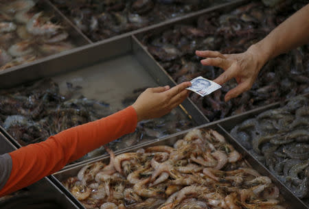 A customer pays for shrimp at a wet market in Singapore March 23, 2016. REUTERS/Edgar Su/Files GLOBAL BUSINESS WEEK AHEAD PACKAGE - SEARCH 'BUSINESS WEEK AHEAD 24 OCT' FOR ALL IMAGES