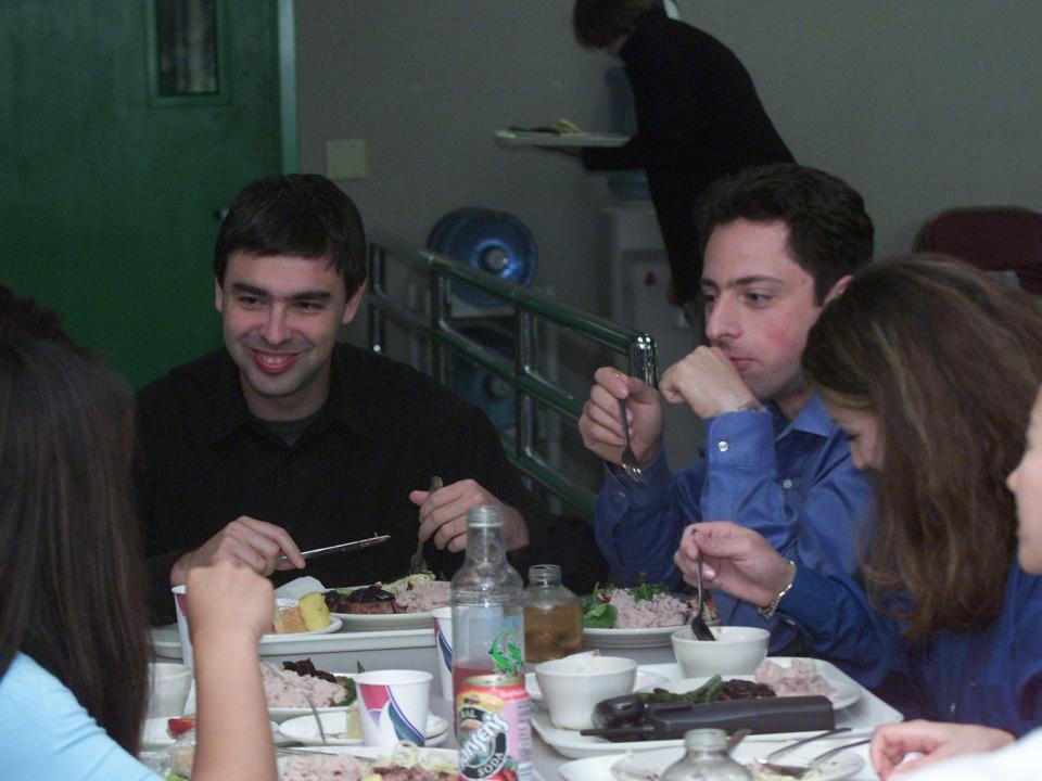 Larry Page and Sergey Brin laugh while eating lunch with Google employees