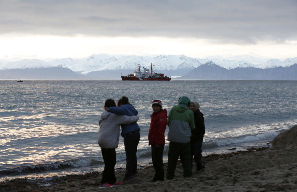 Local children stand on the shore as the Coast Guard ship Des Groseilliers sits in the waters near the Arctic community of Pond Inlet, Nunavut August 23, 2014. Picture taken August 23, 2014. REUTERS/Chris Wattie (CANADA - Tags: MILITARY POLITICS)