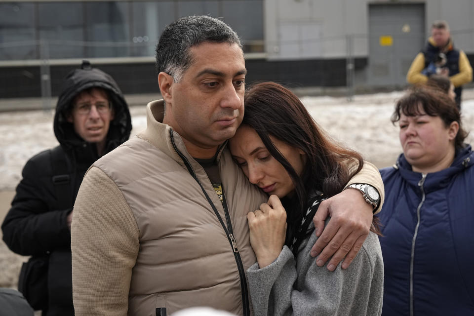 People stand at a makeshift memorial in front of the Crocus City Hall on the western outskirts of Moscow, Russia, Tuesday, March 26, 2024. Russian state news agency Tass says 22 victims of the concert hall attack that killed more than 130 people remain in serious condition in the hospital. (AP Photo/Alexander Zemlianichenko)