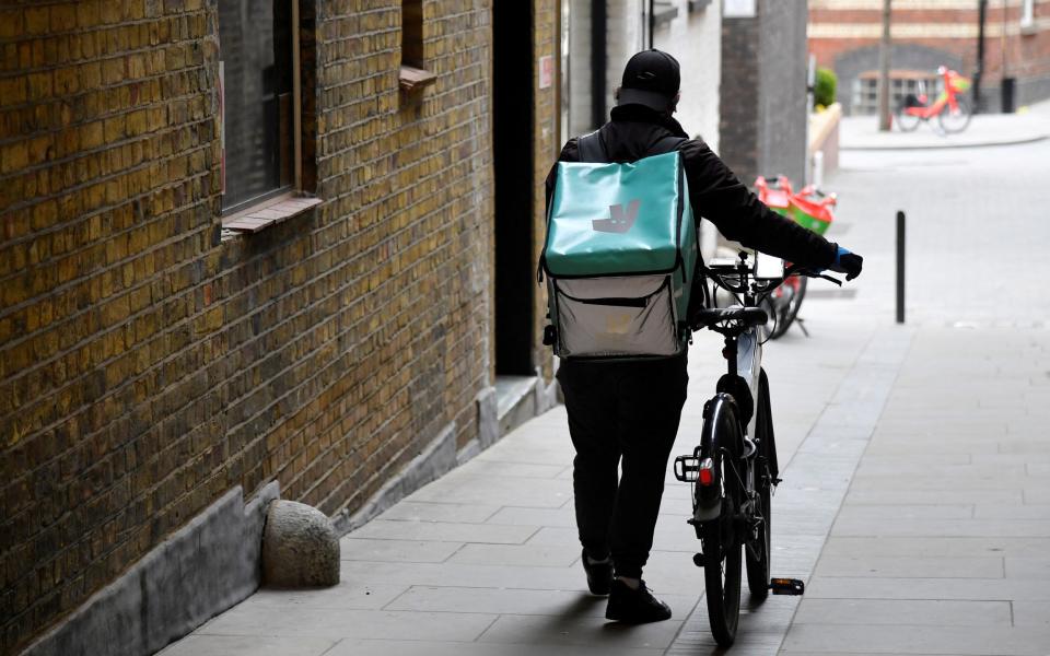 A Deliveroo delivery rider pushes a bicycle in London, Britain - TOBY MELVILLE / REUTERS