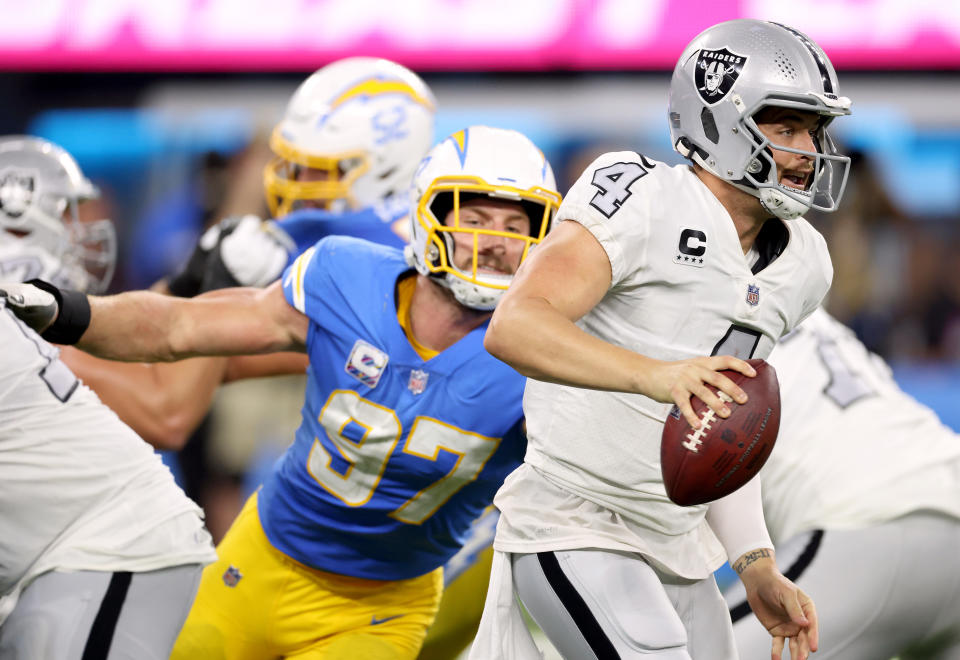 Derek Carr #4 of the Las Vegas Raiders scrambles away from Joey Bosa #97 of the Los Angeles Chargers during a 28-14 loss to the Chargers at SoFi Stadium on October 04, 2021 in Inglewood, California. (Photo by Harry How/Getty Images)