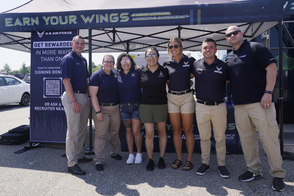 The recruiting team poses together at the U.S. Air Force recruiting tent prior to a NASCAR race at the New Hampshire Motor Speedway, Sunday, July 17, 2022, in Loudon, N.H. These are tough times for military recruiters. All services are having problems finding young people who want to join and can meet the physical, mental and moral requirements. Recruiters are offering bigger bonuses and other incentives to those who sign up. And they are seizing on the boost that Hollywood may offer – such as the buzz over Top Gun. (AP Photo/Charles Krupa)
