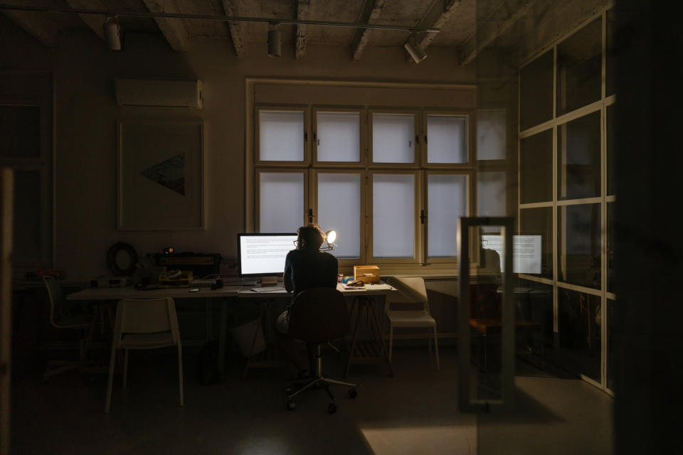 Photo of a man sitting at a desktop computer and working during a late-night shift