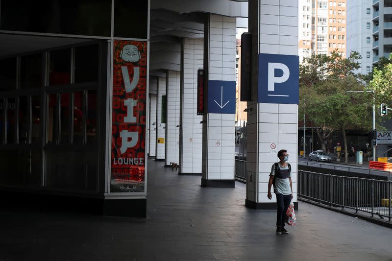 A man walks by an almost empty area of the city following the implementation of stricter social-distancing and self-isolation rules to limit the spread of the coronavirus disease (COVID-19) in Sydney