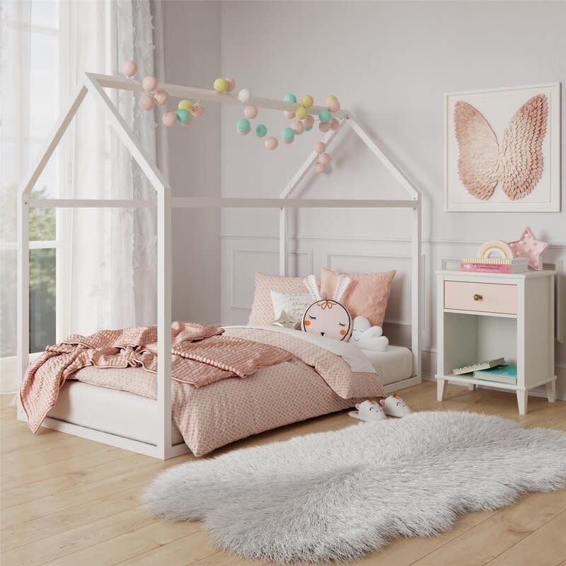 Child's bedroom with a house-shaped bed frame, decorative pillows, and a side table