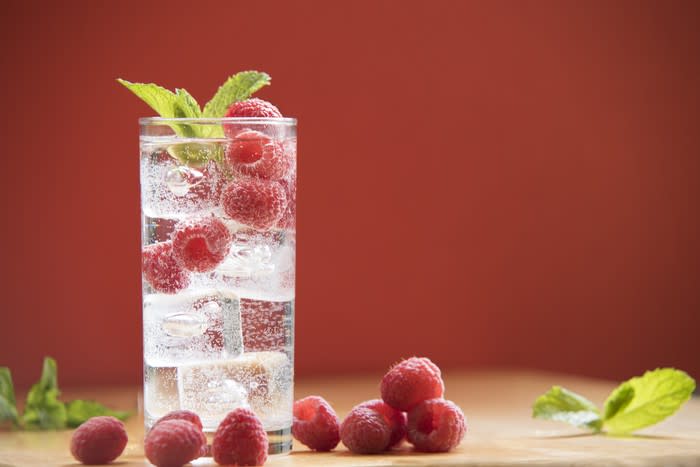 iced seltzer in glass with raspberries and mint