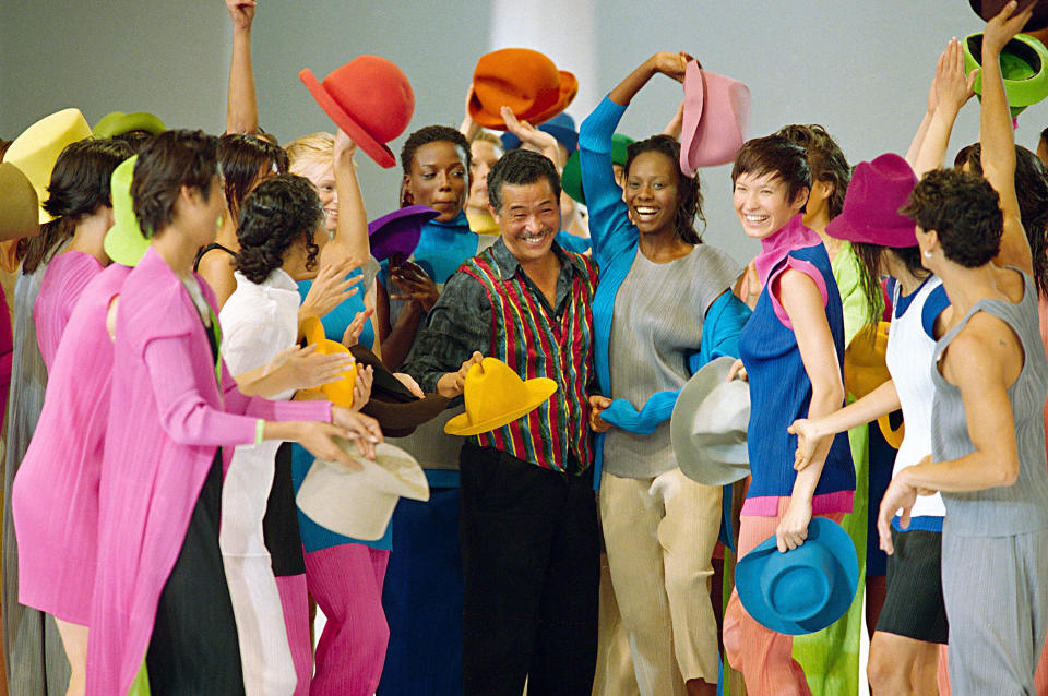 FILE - Models in colorful clothes surround Japanese designer Issey Miyake after the presentation of his "1994 Spring-Summer ready-to-wear collection" presented in Paris, Oct. 8, 1993. Miyake, who built one of Japan’s biggest fashion brands and was known for his boldly sculpted pleated pieces as well as former Apple CEO Steve Jobs’ black turtlenecks, has died. He was 84. He died Aug. 5, 2022, of liver cancer, Miyake Design Office said Tuesday, Aug. 9. (AP Photo/Lionel Cironneau, File)