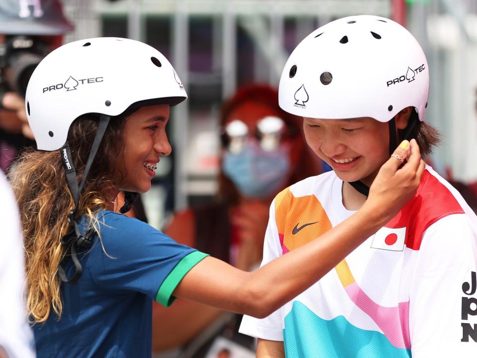 Rayssa Leal of Team Brazil puts her hand to the face of Momiji Nishiya of Team Japan during the Tokyo Olympic street skating competition.